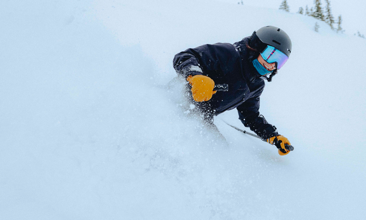 Person skiing down a snowy slope with a helmet and goggles.