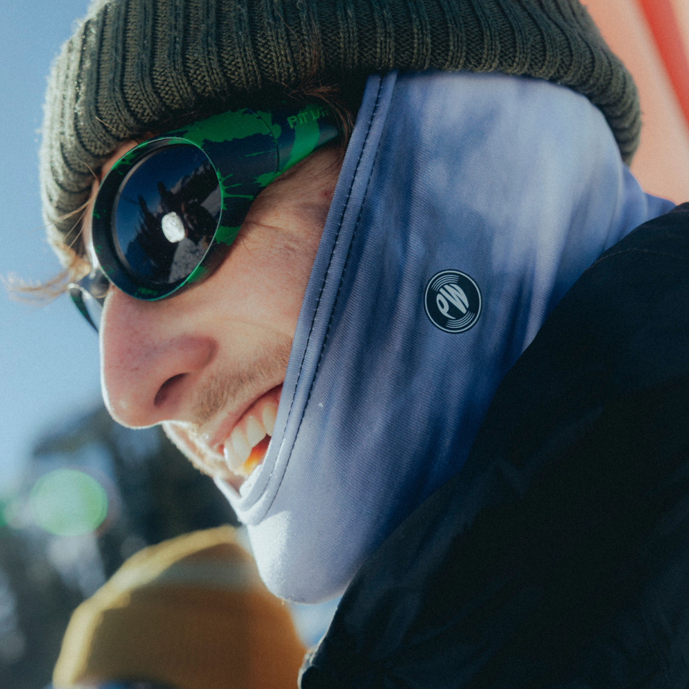 Person wearing a beanie, sunglasses, and a soft single tube neck tube for skiing
